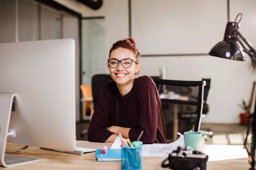 Young professional woman smiling at her desk, representing freelancers working in Dubai.